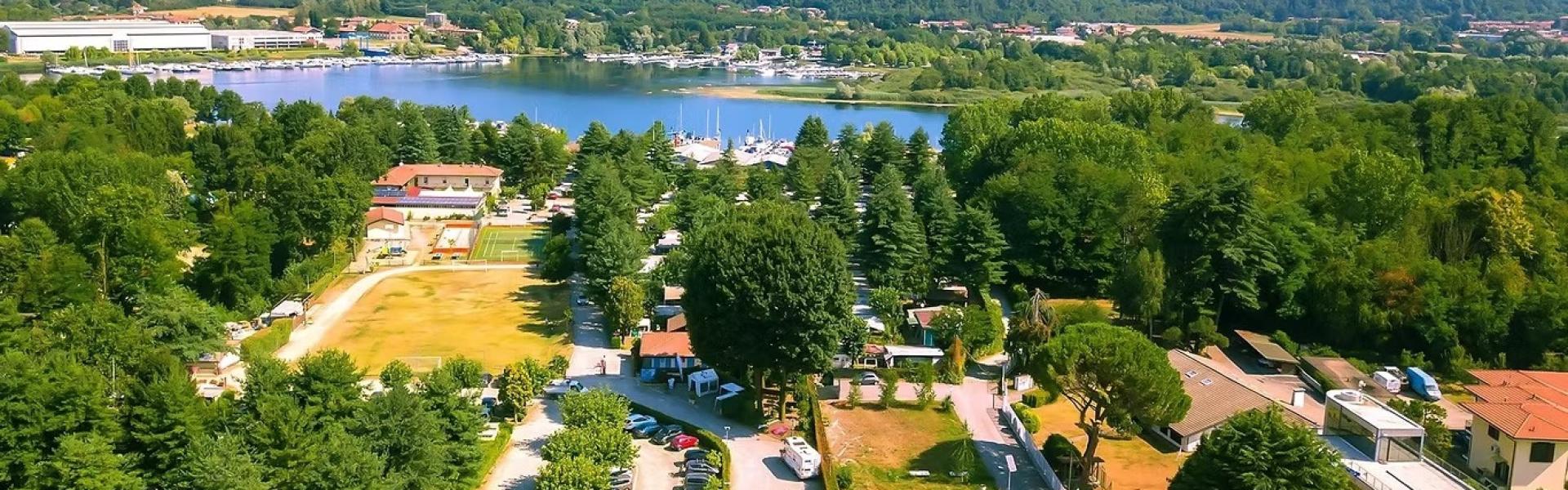 Vista aerea di un campeggio verdeggiante vicino a un lago tranquillo e colline.