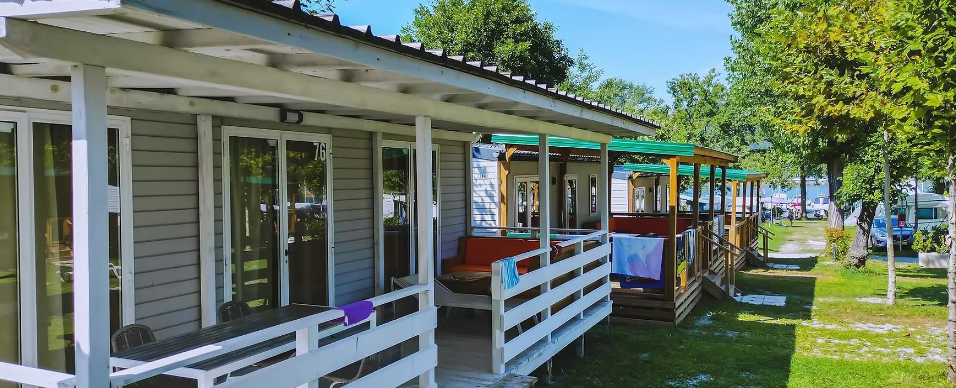 Bungalow colorati in fila, immersi nel verde, evocano relax e vacanze estive al sole.