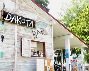 Un bar rustico, accogliente, con bici parcheggiata e atmosfera estiva, rilassante e invitante.