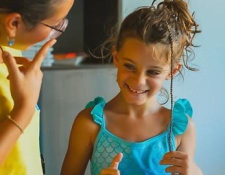 Due bambine sorridenti condividono un momento di gioia e complicità in un ambiente colorato.
