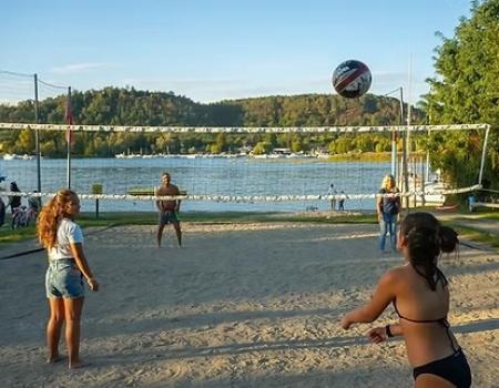 Partita di beach volley al tramonto, gioia e relax vicino al lago.