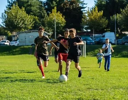 Ragazzi corrono su un campo verde, inseguendo un pallone, pieni di energia e gioia.