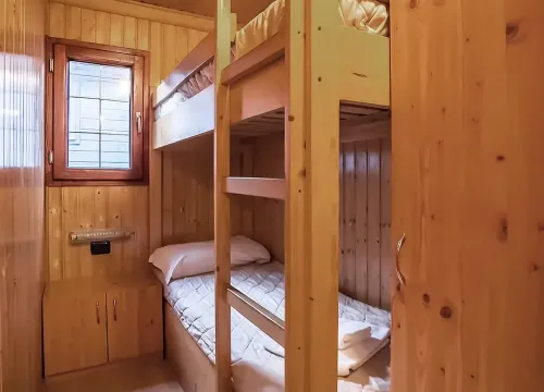 Camera in legno caldo, letti a castello, atmosfera accogliente e intima.