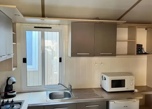 Cucina moderna e compatta, luminosa, con elettrodomestici essenziali e un'atmosfera accogliente.
