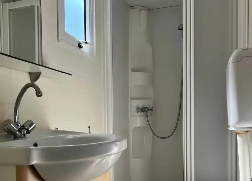 Bagno compatto e luminoso con doccia, lavabo e WC, trasmette pulizia e semplicità.