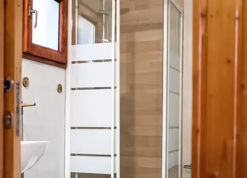 Bagno luminoso e accogliente con doccia moderna, bidet e dettagli in legno caldi.
