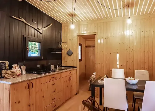 Accogliente cucina in legno, atmosfera calda, dettagli rustici, luci soffuse, tavolo elegante.