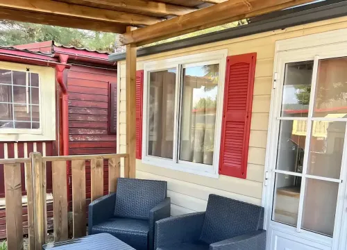 Terrazza accogliente con sedie intrecciate, atmosfera calda e rilassante tra casette colorate.