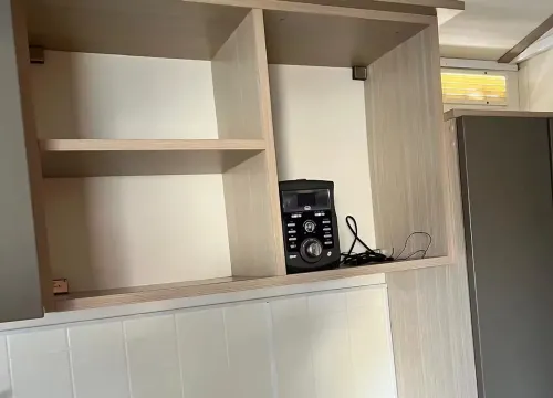 Cucina moderna, scaffale vuoto, microonde e stereo, atmosfera ordinata e minimalista.