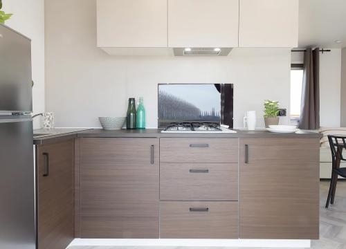 Cucina moderna, minimalista, luminosa, con legno caldo e tocchi di verde naturale.