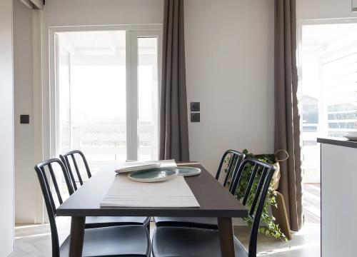 Sala da pranzo luminosa, tavolo elegante, sedie nere, pianta verde, atmosfera accogliente.