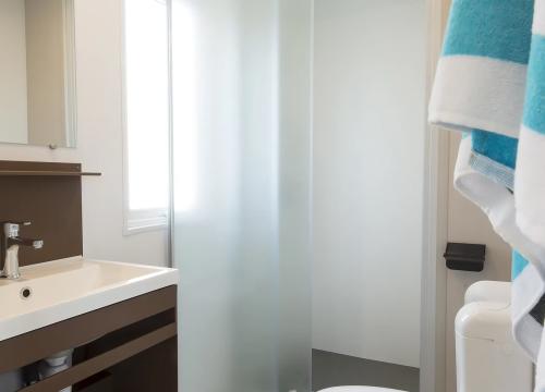 Bagno moderno e luminoso con doccia in vetro, asciugamani colorati e atmosfera fresca.