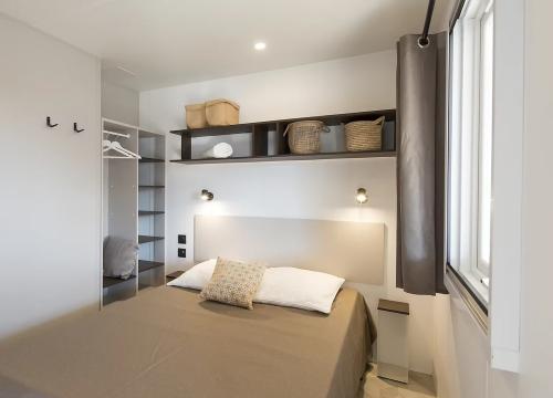 Camera moderna, accogliente, con letto matrimoniale, scaffali ordinati e luce calda, atmosfera rilassante.