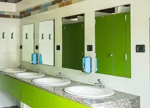 Bagno moderno e luminoso con lavandini bianchi e pareti verdi, atmosfera fresca e pulita.