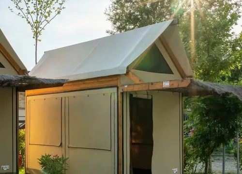 Tenda glamping al tramonto, immersa nella natura, atmosfera serena e accogliente.