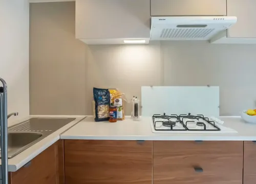 Cucina moderna, luminosa, con fornelli, dispensa e frutta fresca. Atmosfera accogliente e ordinata.