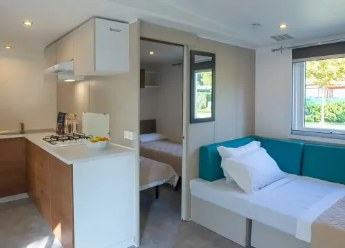Moderna casa mobile luminosa, cucina compatta, divano accogliente, camera da letto intima.