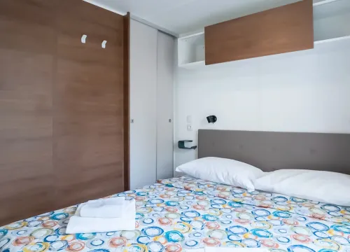 Camera accogliente con letto colorato, armadio in legno e luci soffuse.