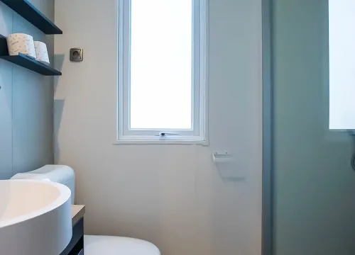 Bagno moderno e luminoso, con doccia in vetro e scaffali minimalisti.