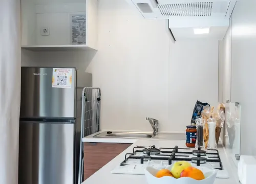 Cucina moderna e luminosa, frutta fresca in primo piano, ordine e pulizia.