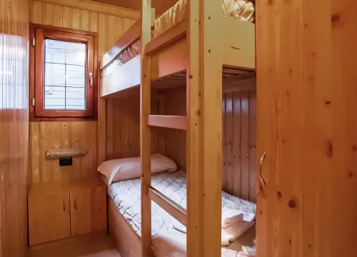 Camera accogliente in legno con letti a castello, calda e intima, ideale per relax.