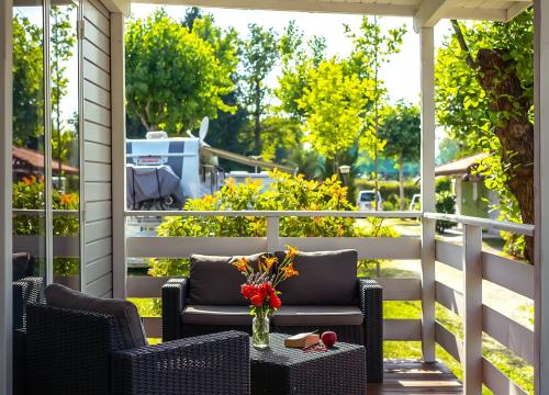 Veranda accogliente con fiori, libro e sole, immersa nella natura rigogliosa.