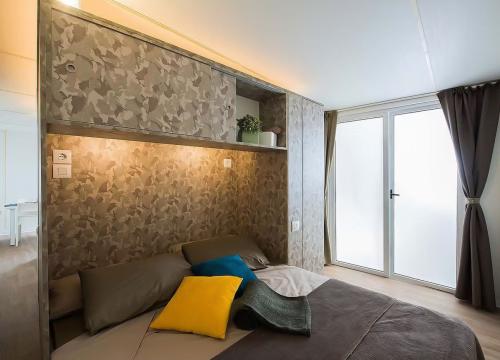 Camera accogliente con letto, cuscini colorati e luce soffusa, atmosfera calda e rilassante.