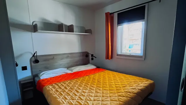 Camera accogliente, letto matrimoniale colorato, luce soffusa, atmosfera calda e rilassante.