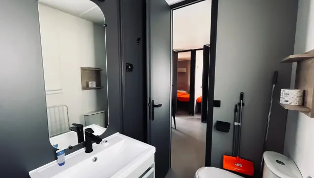 Bagno moderno e minimalista, con dettagli neri e arancioni, trasmette ordine e semplicità.