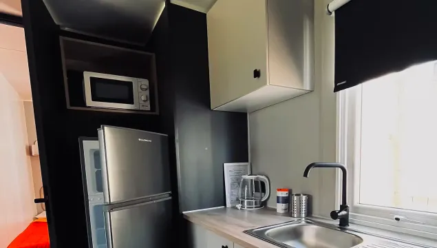 Cucina moderna e compatta con elettrodomestici in acciaio, luminosa e funzionale.