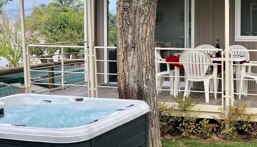 Terrazza accogliente con jacuzzi, tavolo apparecchiato, natura verde e tranquillità rilassante.