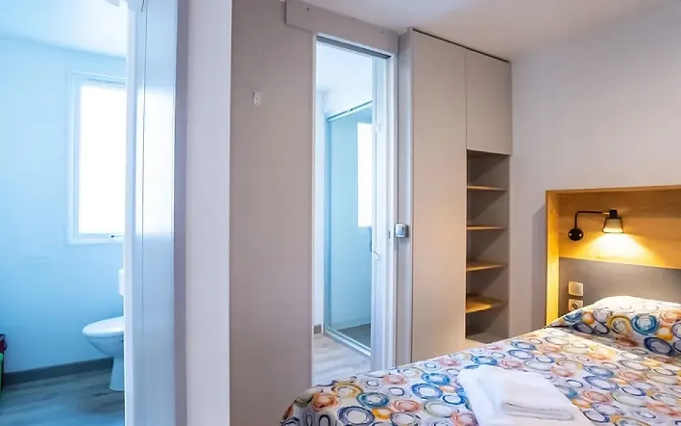 Camera accogliente e luminosa, letto colorato, bagno moderno, atmosfera rilassante e ordinata.
